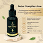Hair growth serum bottle with dropper on a natural stone base, surrounded by leaves, against a beige background.